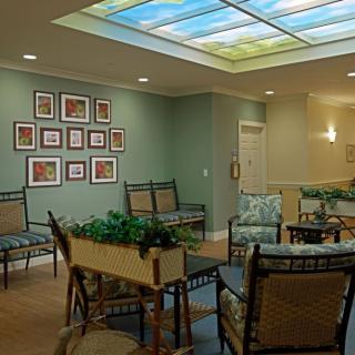 A well-decorated waiting room with comfortable seating, overhead lighting, and artwork on the walls.