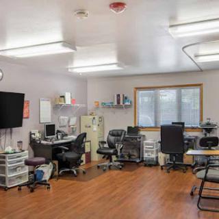 A modern office space featuring workstations with computers, chairs, and storage units.