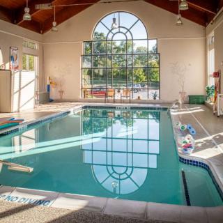 A bright indoor swimming pool with large windows allowing natural light to fill the space.