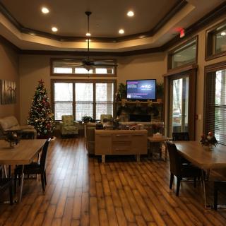 A cozy living room featuring a Christmas tree, comfortable seating, and a television.