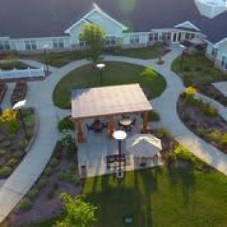 Aerial view of a landscaped garden with pathways and a central pavilion surrounded by buildings.