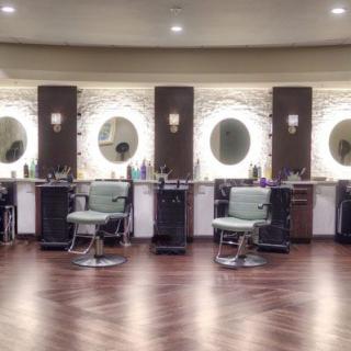A modern barbershop with stylish chairs and illuminated mirrors.