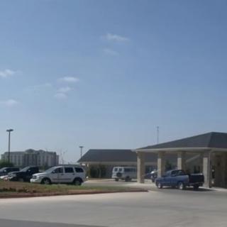 A drive-through area of a building with cars parked nearby on a sunny day.