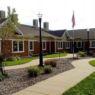 A picturesque building with a winding pathway, well-maintained garden, and flagpole.