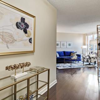 A modern living room with elegant decor, featuring a blue sofa and abstract artwork.