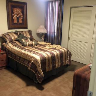 A cozy bedroom with a neatly made bed, decorative pillows, and a side table lamp.