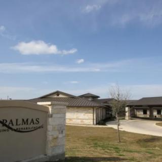 A view of a building complex with a sign in the foreground under a blue sky.