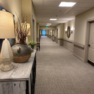 A well-lit, carpeted hallway with decorative lamps and furniture.