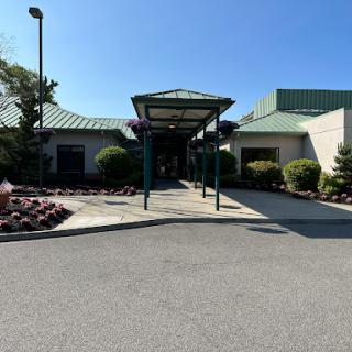 The entrance of a well-maintained building surrounded by vibrant landscaping under a clear blue sky.