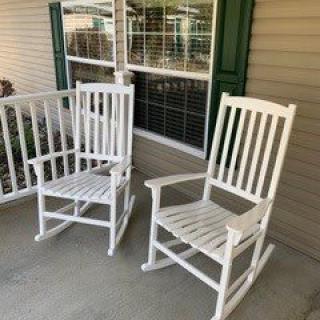 Two white rocking chairs on a porch.
