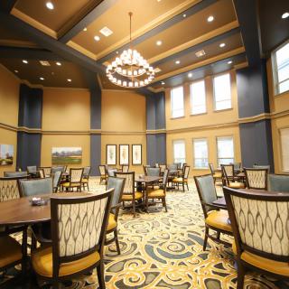 A spacious and elegantly decorated dining room with multiple tables and a large chandelier.