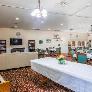 A spacious communal dining and living area with tables, chairs, and a television.