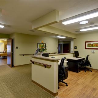 A modern reception area with desks and chairs, featuring a well-lit corridor.