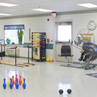 A physical therapy room equipped with exercise machines and colorful pins for rehabilitation activities.