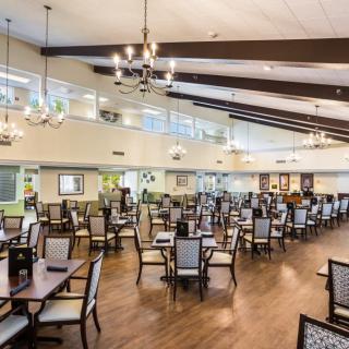 A spacious dining hall with elegant chandeliers and neatly arranged tables and chairs.