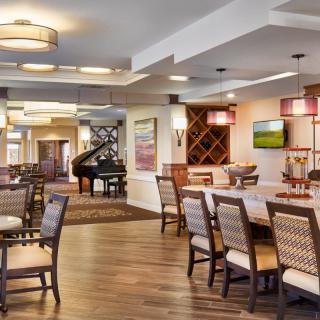 A modern and cozy dining room with elegant furniture and a grand piano in the corner.