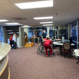 A busy healthcare facility with staff assisting patients and various medical equipment present.