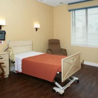 A hospital room with a bed, medical equipment, and a comfortable chair.