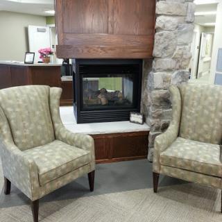 A cozy seating area featuring two patterned chairs beside a modern fireplace.