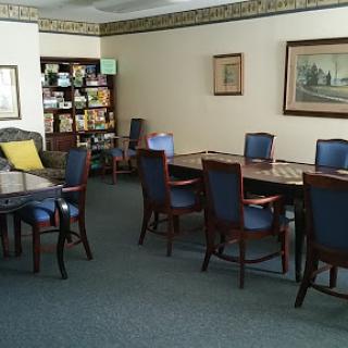 A well-furnished meeting room featuring tables and chairs, with a bookshelf in the background.