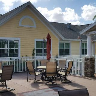 An outdoor patio area with tables, chairs, and an umbrella in front of a yellow building.