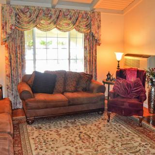 A cozy living room with a sofa, armchair, and a large window adorned with curtains.