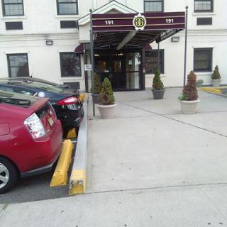 A view of a hotel entrance with parked cars in front.