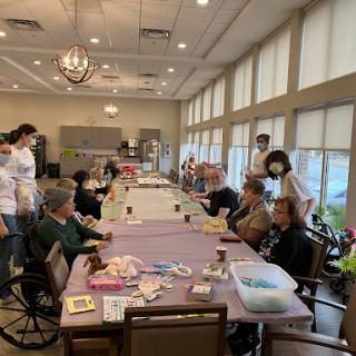 A lively community gathering where individuals come together around a table, engaging in activities and enjoying each other's company.