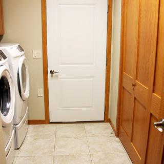 A cozy laundry room featuring a washing machine and dryer, with wooden doors and tiled flooring.