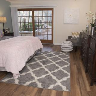 A cozy bedroom featuring a large rug, wooden flooring, and elegant furniture.