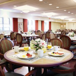 A well-arranged dining room with tables set for breakfast, featuring flowers in the center.
