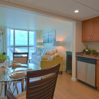A cozy apartment interior featuring a living room with modern furnishings, an open kitchen, and a dining area.