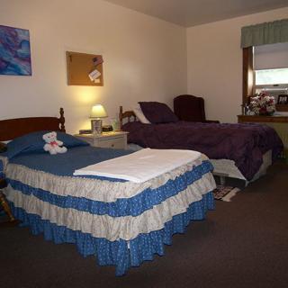 A cozy bedroom with two beds and a nightstand featuring a lamp.
