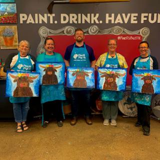 Participants proudly display their artwork after a fun paint and sip class.