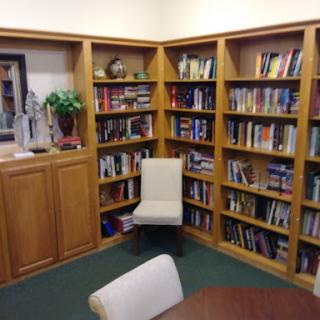 A cozy corner of a library featuring wooden bookshelves filled with various books and a comfortable chair.