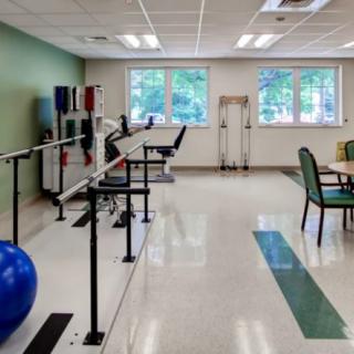 A rehabilitation therapy room with exercise equipment and parallel bars.