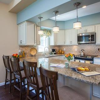 A modern kitchen with a granite countertop, bar stools, and pendant lighting.