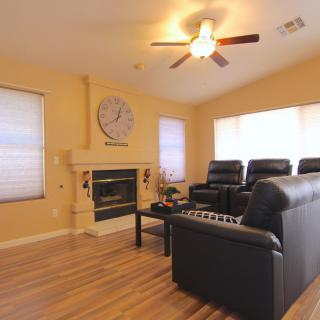 A cozy living room with a home theater setup, featuring leather seating and a fireplace.