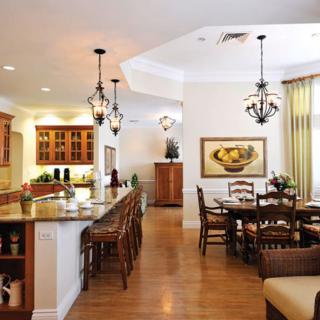 A modern open-plan kitchen and dining area with elegant chandeliers and wood flooring.