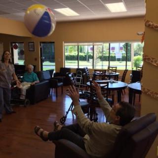 Seniors enjoying a recreational activity with a beach ball indoors.