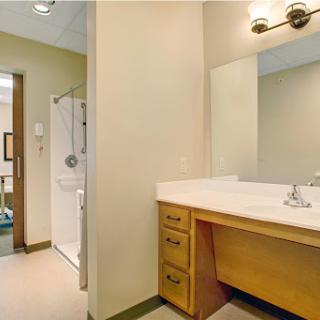 A well-lit bathroom featuring a sink vanity, mirror, and shower.