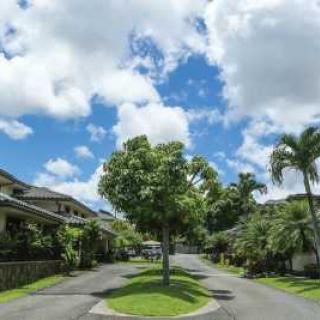A scenic residential neighborhood with lush greenery and a bright, cloudy sky.