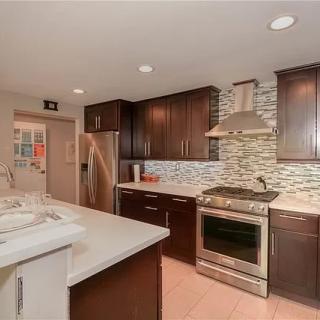 A modern kitchen with dark cabinets, stainless steel appliances, and a tile backsplash.