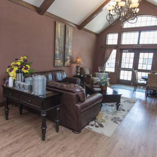 A cozy living room with leather sofas, a chandelier, and large windows.