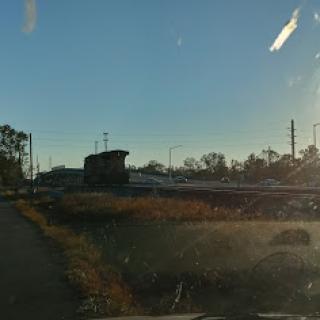 A serene early morning view of a rural landscape with buildings along the road illuminated by the rising sun.