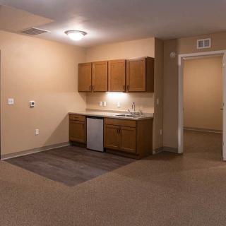 A minimalist kitchen area with brown cabinets and beige walls in an empty apartment.