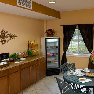 A cozy dining area with a small refrigerator, decorative elements, and a table set for breakfast.