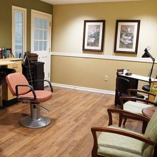 A well-organized barbershop with a styling chair, desk, and seating area.
