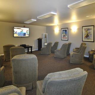 A comfortable lounge area with multiple chairs facing a wall-mounted television.