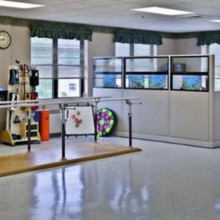 A physical therapy room equipped with parallel bars and various rehabilitation equipment.